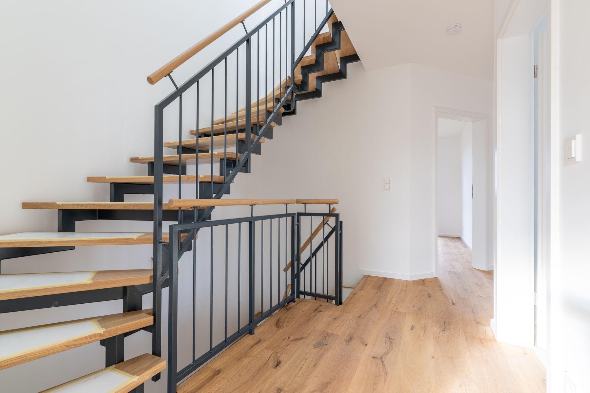 Offene Treppe aus schwarzem Stahl mit Eichenstufen